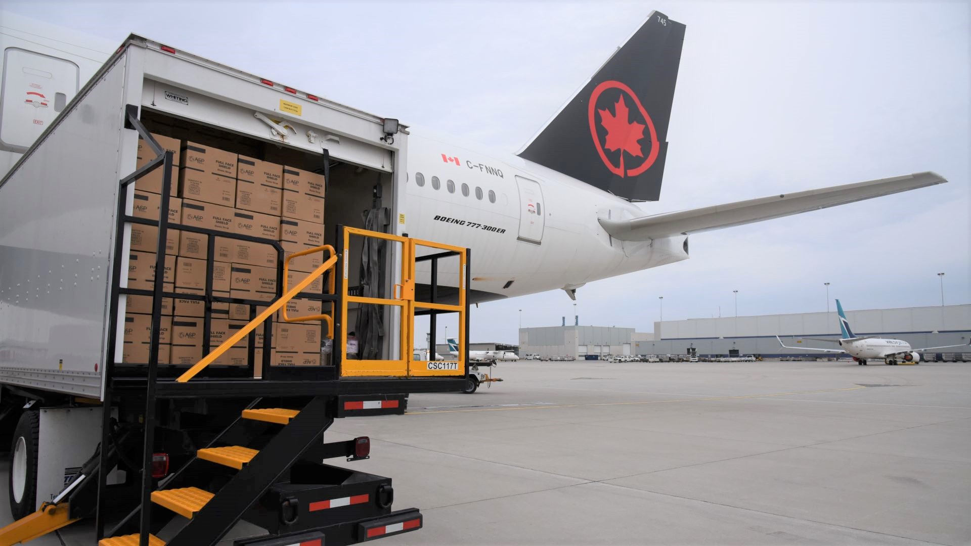 Tail end of an Air Canada jet with cargo loaded in rear door.