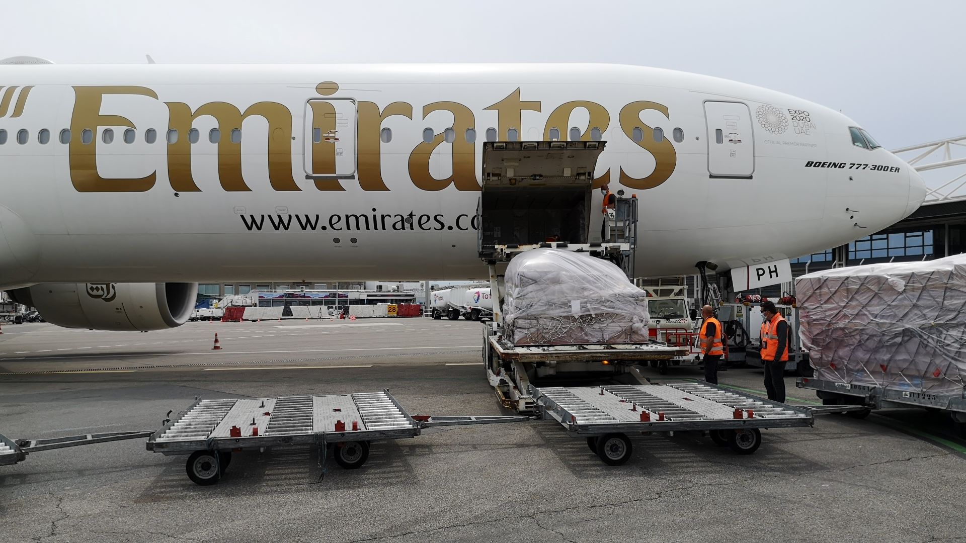 Close up photo from side of an Emirates jet, with cargo being loaded in door.