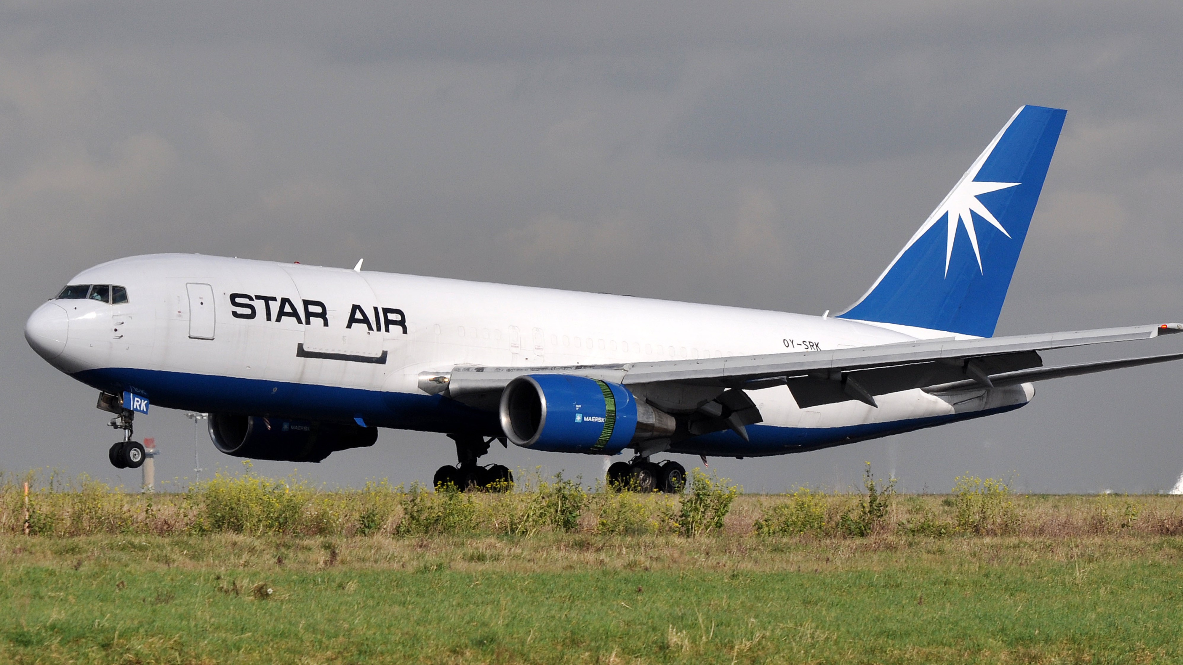 A Maersk cargo jet takes off. Plane has white fuselage and blue tail with a star on it.