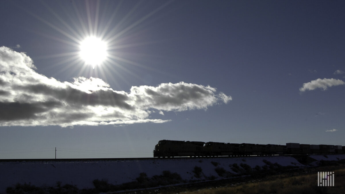 A photograph of a freight train against a bright sky.
