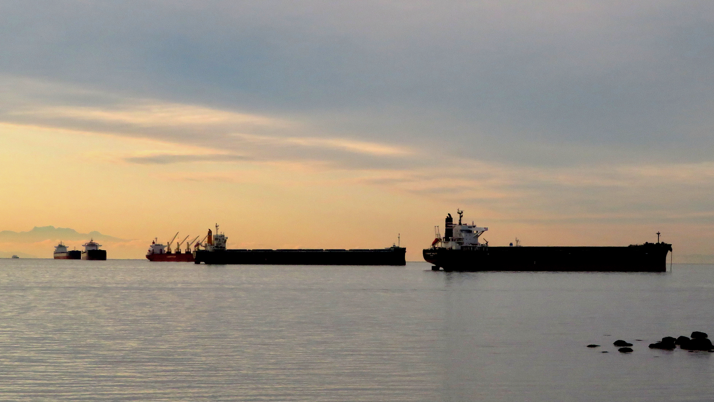 Three ships at anchor near the Port of Vancouver with the sun setting.