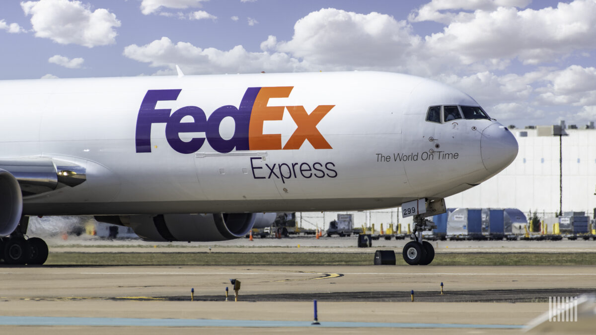 A white FedEx plane, with blue and red lettering, side view of front.