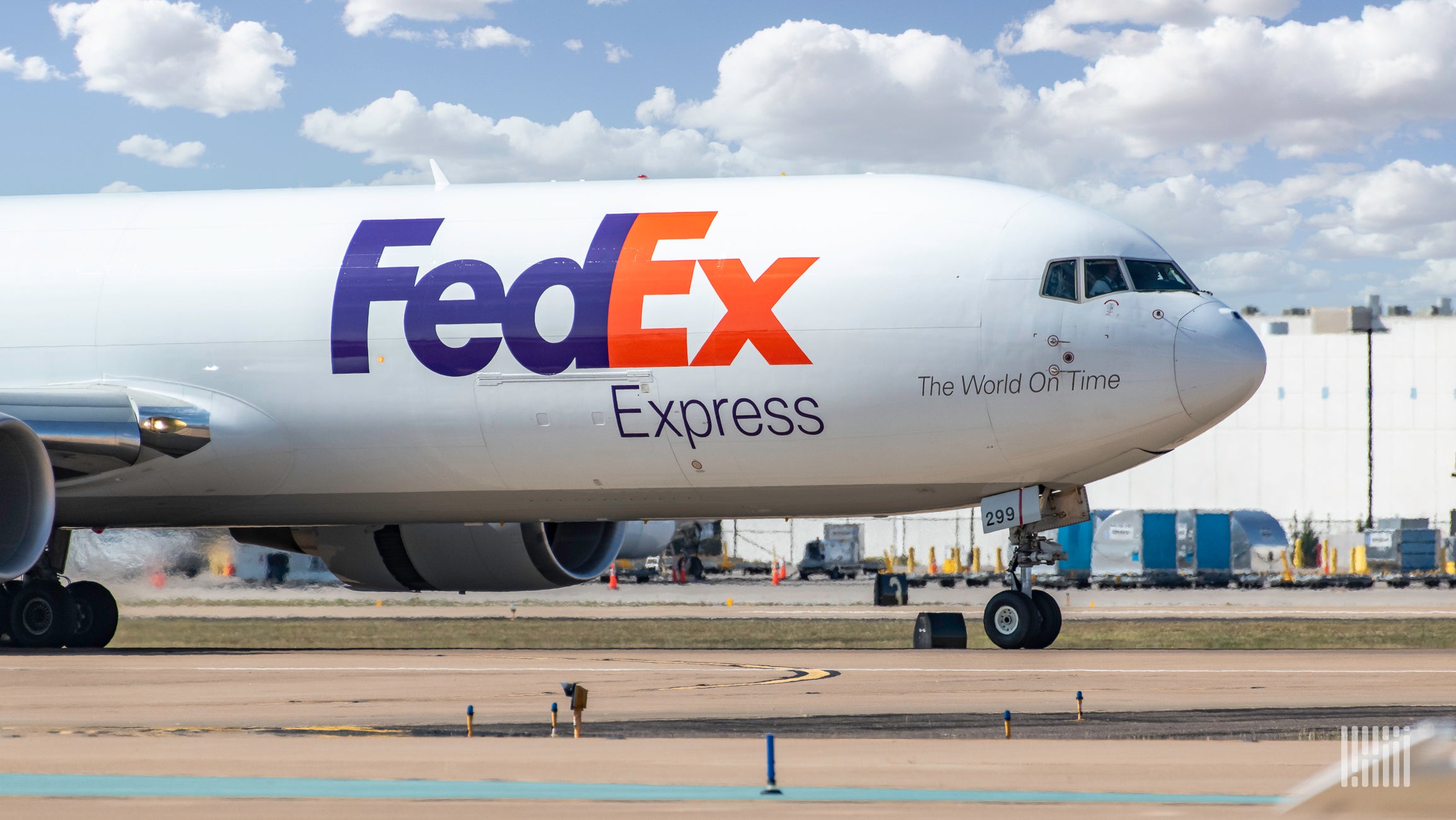 A white FedEx plane, with blue and red lettering, side view of front.