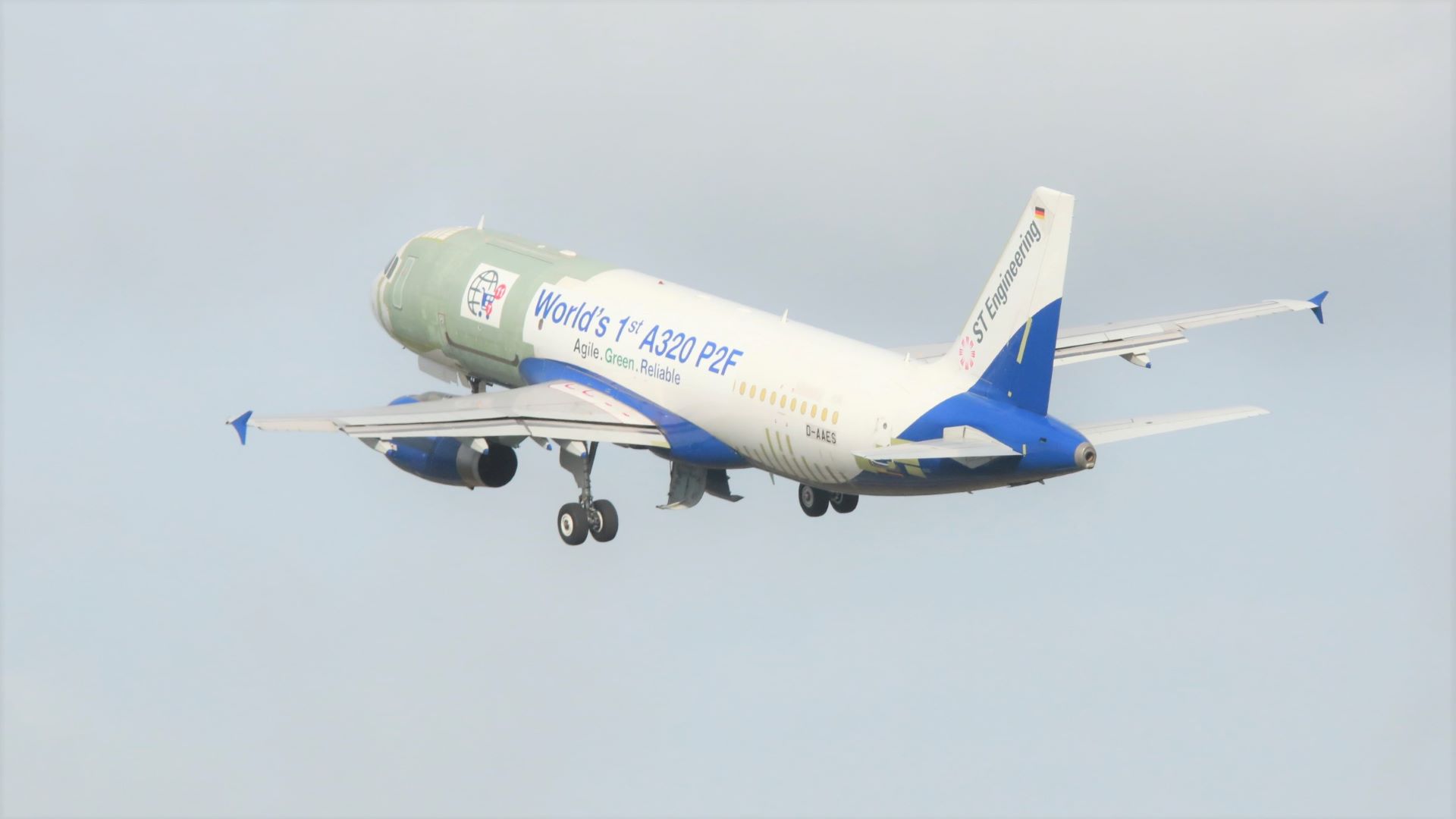 A white plane heading up in the sky with visible patches on fuselage from retrofit work. View from rear.