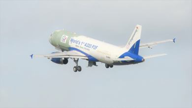 A white plane heading up in the sky with visible patches on fuselage from retrofit work. View from rear.