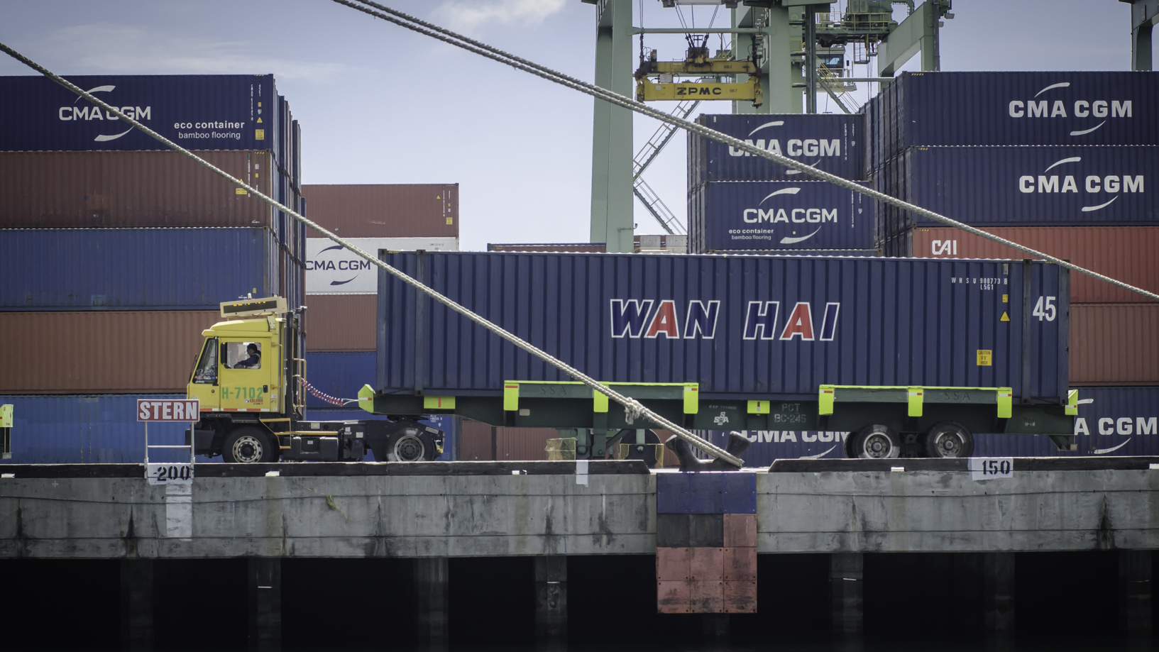 Mullticolored containers on dock with a shuttle truck.