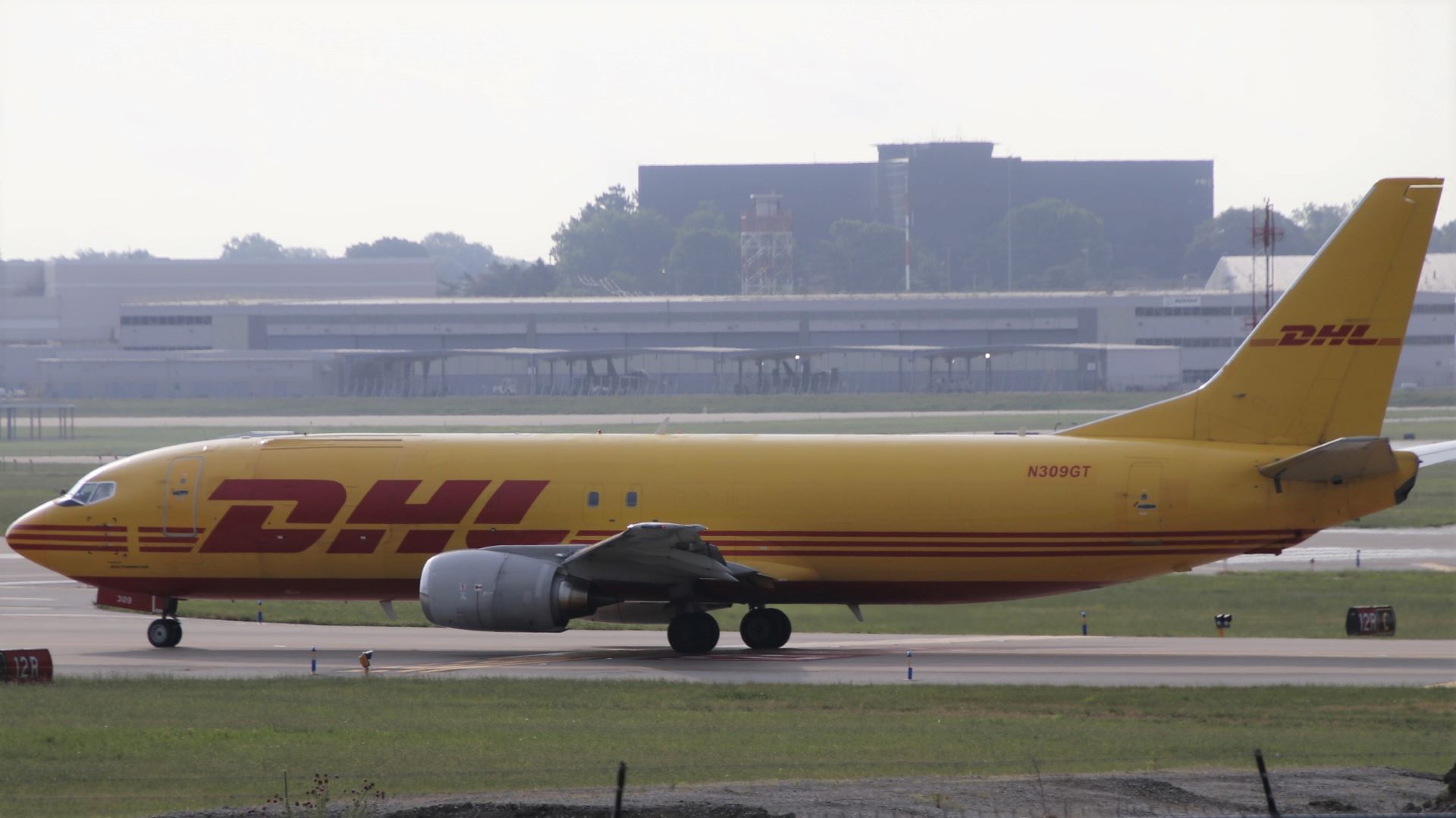A mustard-colored DHL cargo jet on the taxiway.