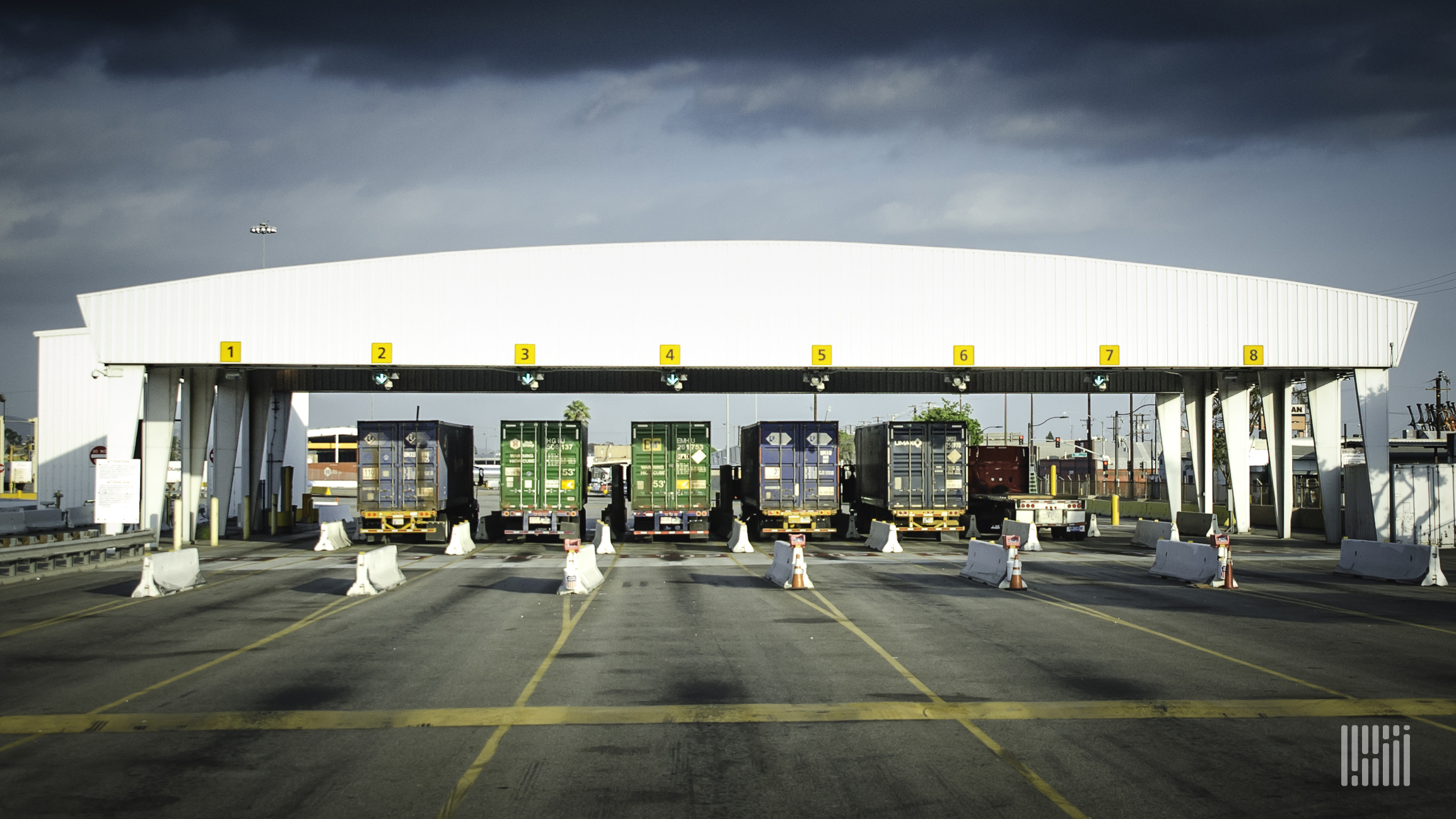 A photograph of trucks hauling intermodal containers out of terminal gate.