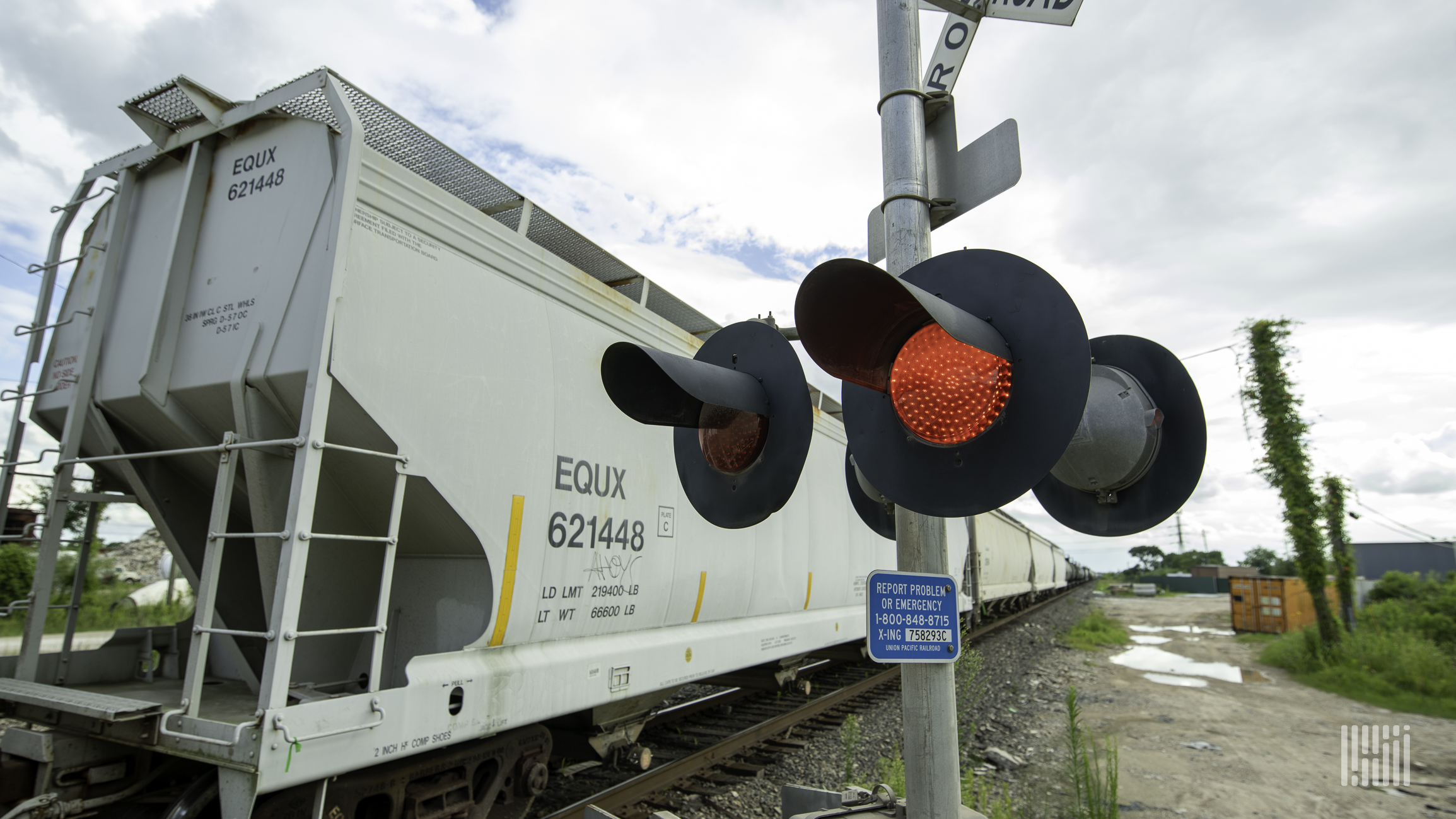 A photograph of a train crossing a rail crossing.