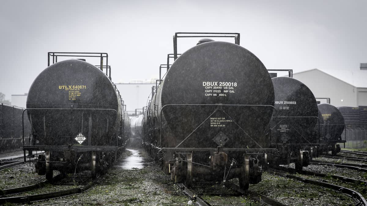 A photograph of tank cars parked in a rail yard in the rain.
