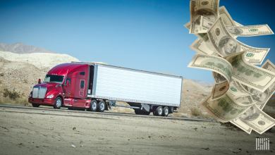 A red an white tractor trailer and $100 bills to illustrate the potential downturn facing the trucking industry..
