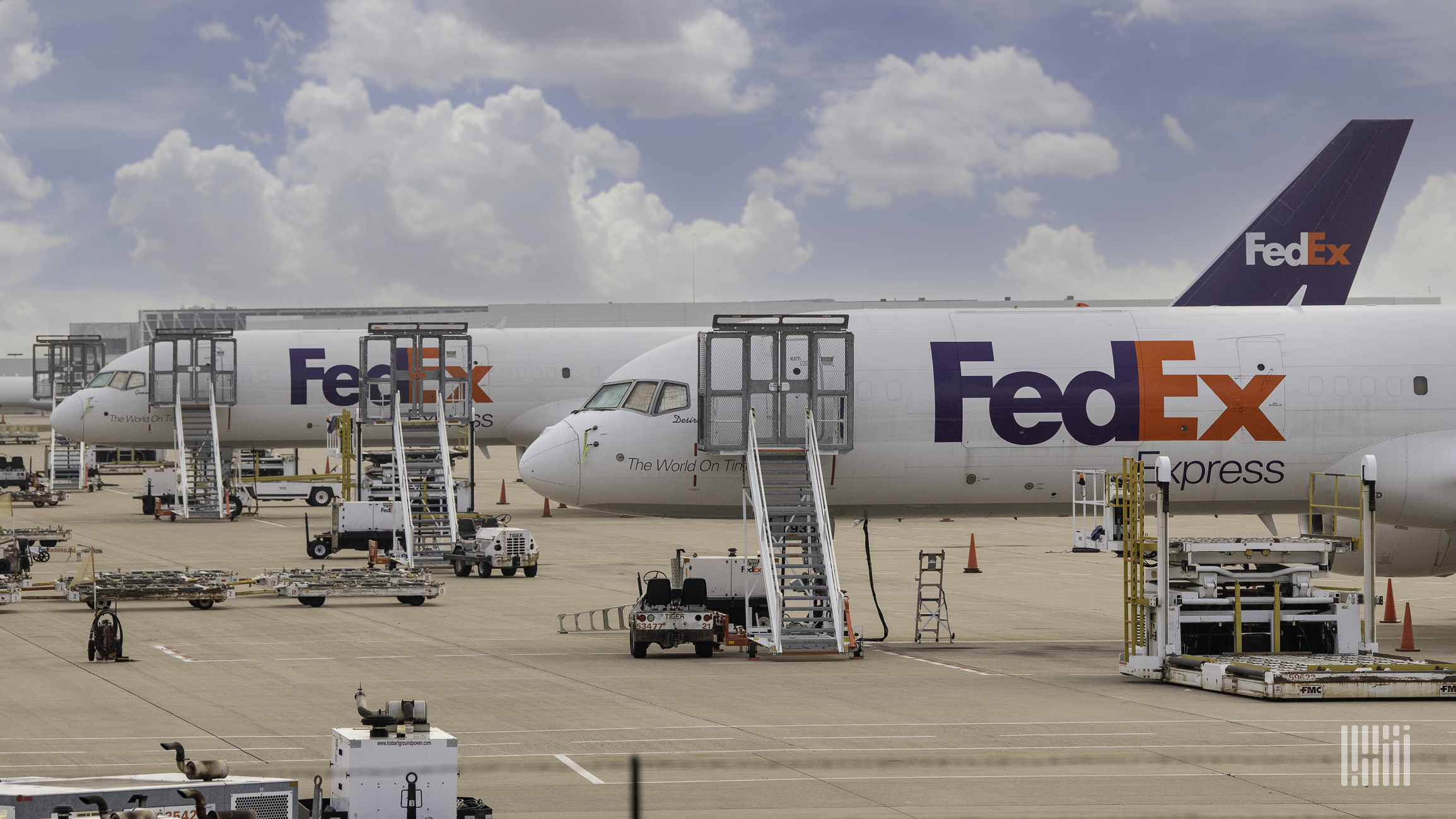 FedEx aircraft on the ground waiting to be loaded on a sunny day.