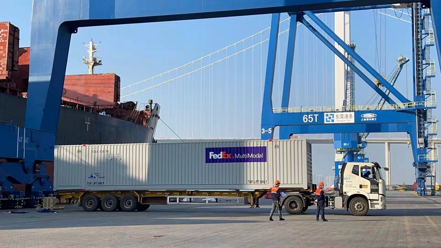 A truck backs up to a vessel so the container can be lifted off and loaded.