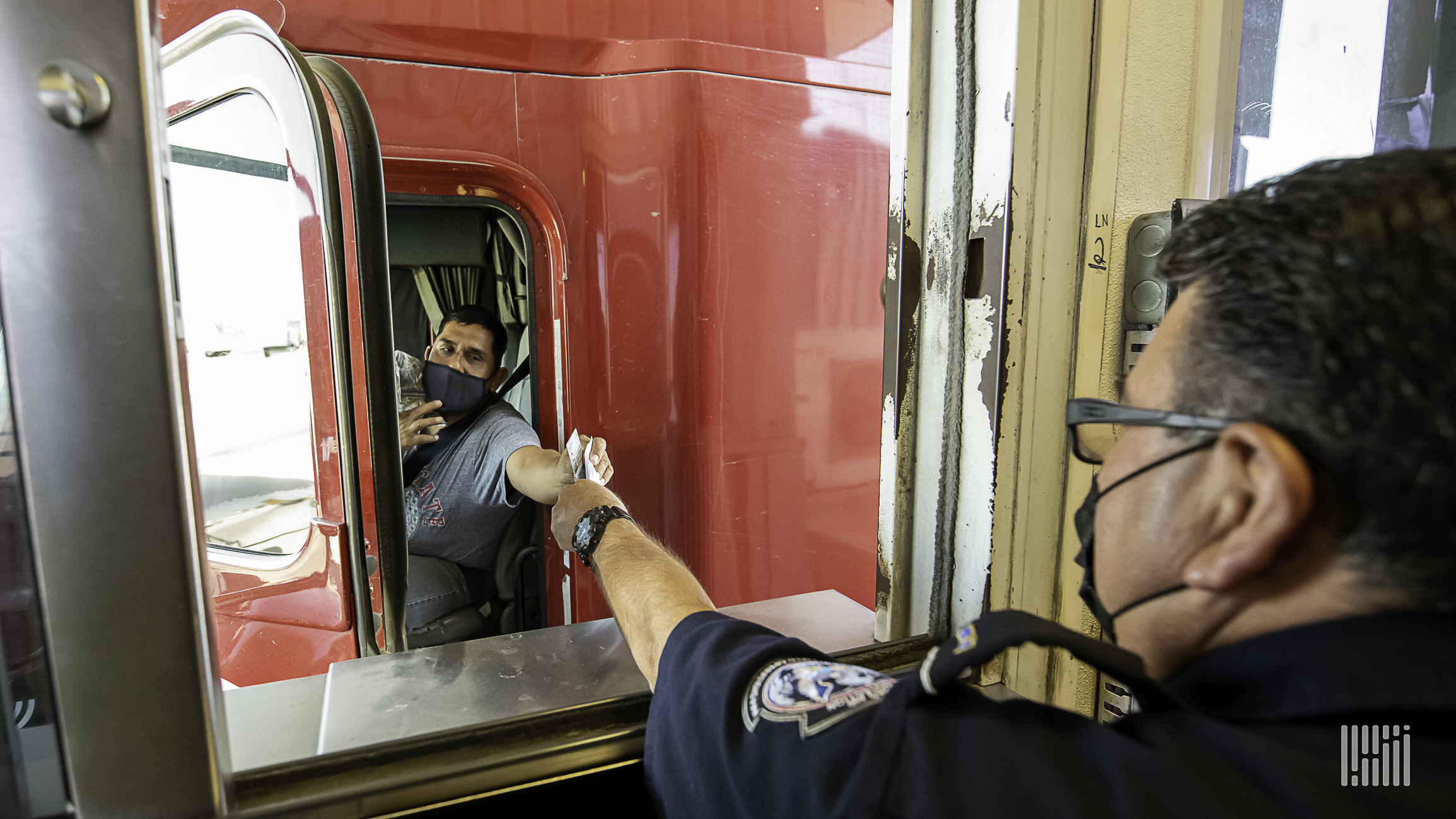 a truck driver handing documents to a US border officer.