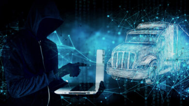 An illustration of a hacker holding a laptop with a tractor trailer to the right.