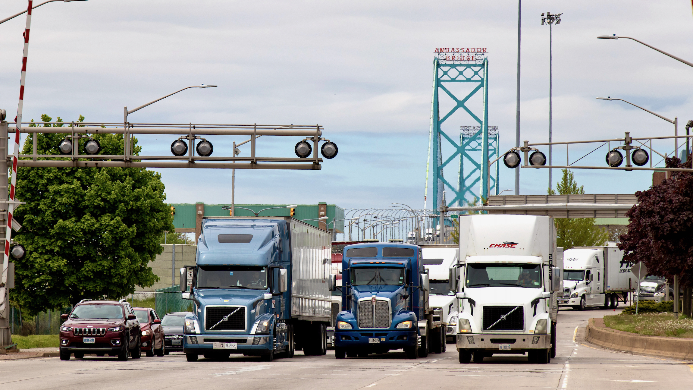 Trucks and vehicles seen leaving the Ambassador Bridge from Detroit entering Canada after crossing the US-Canada border, bridge seen in the background.