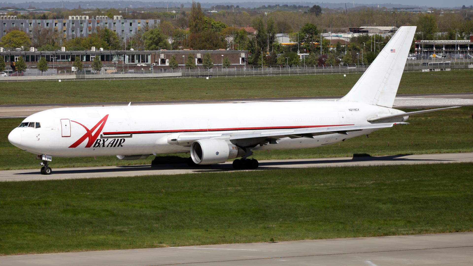 A large white cargo jet with ABX Air lettering rolls down runway.
