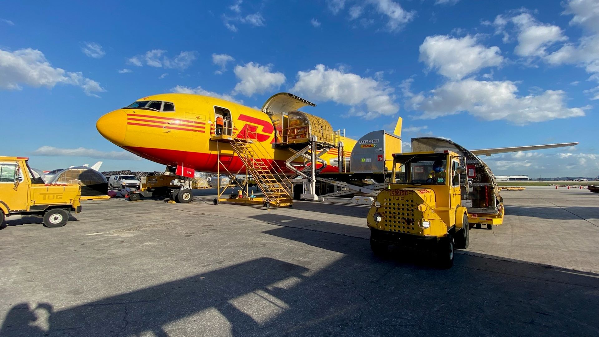 A mustard-colored jet with red DHL lettering on the tarmac.
