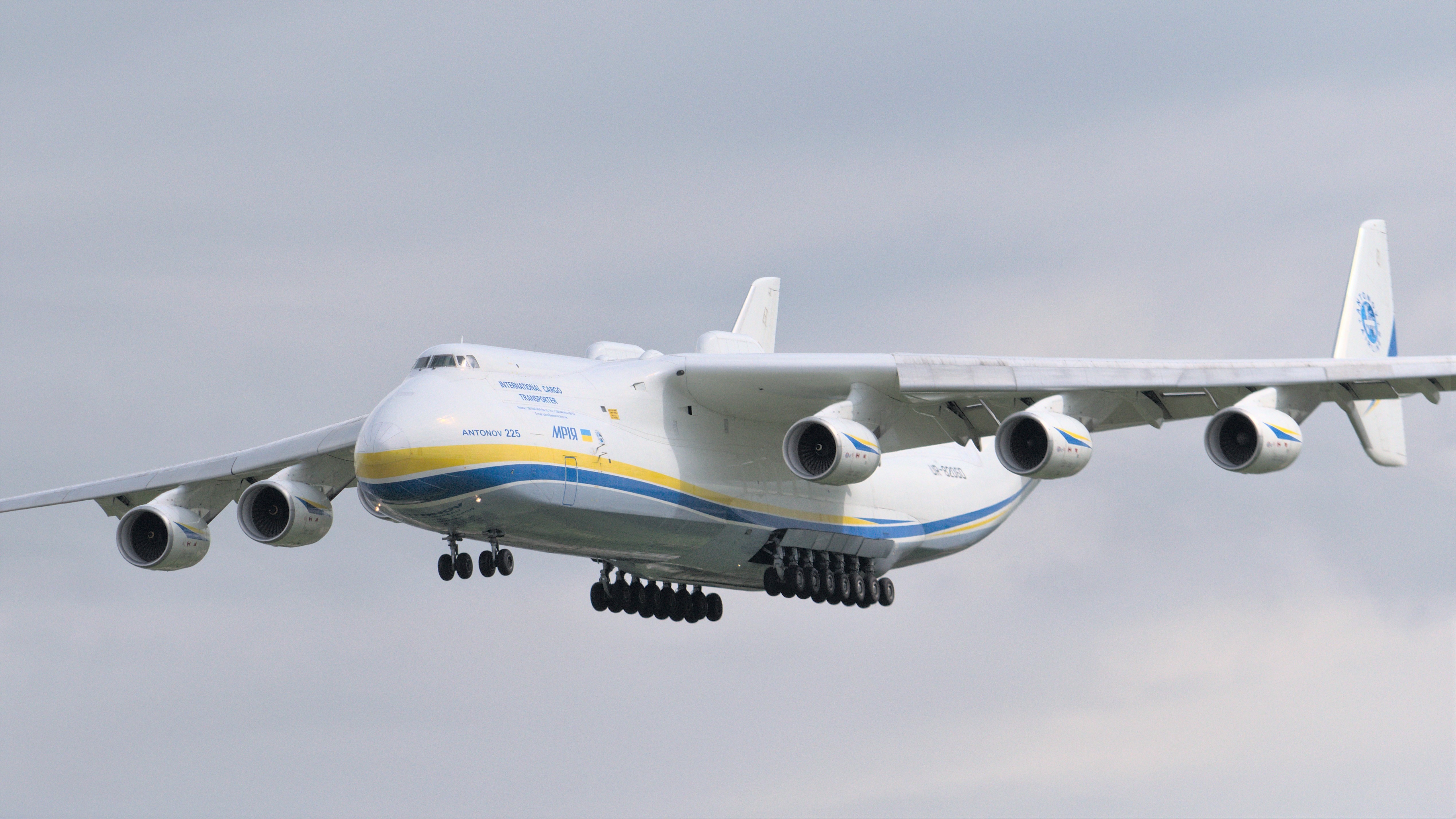 A massive twin-tailed cargo jet with large number of wheels comes in for landing.