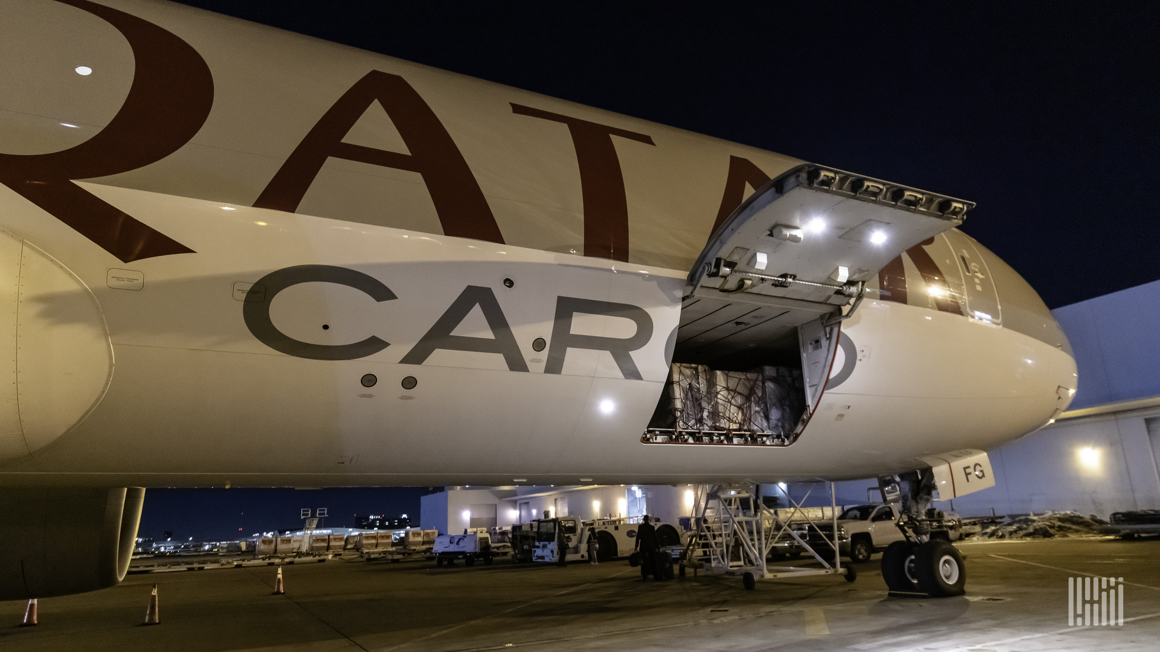 Close up of a Qatar Airways Cargo jet with side door open at night.