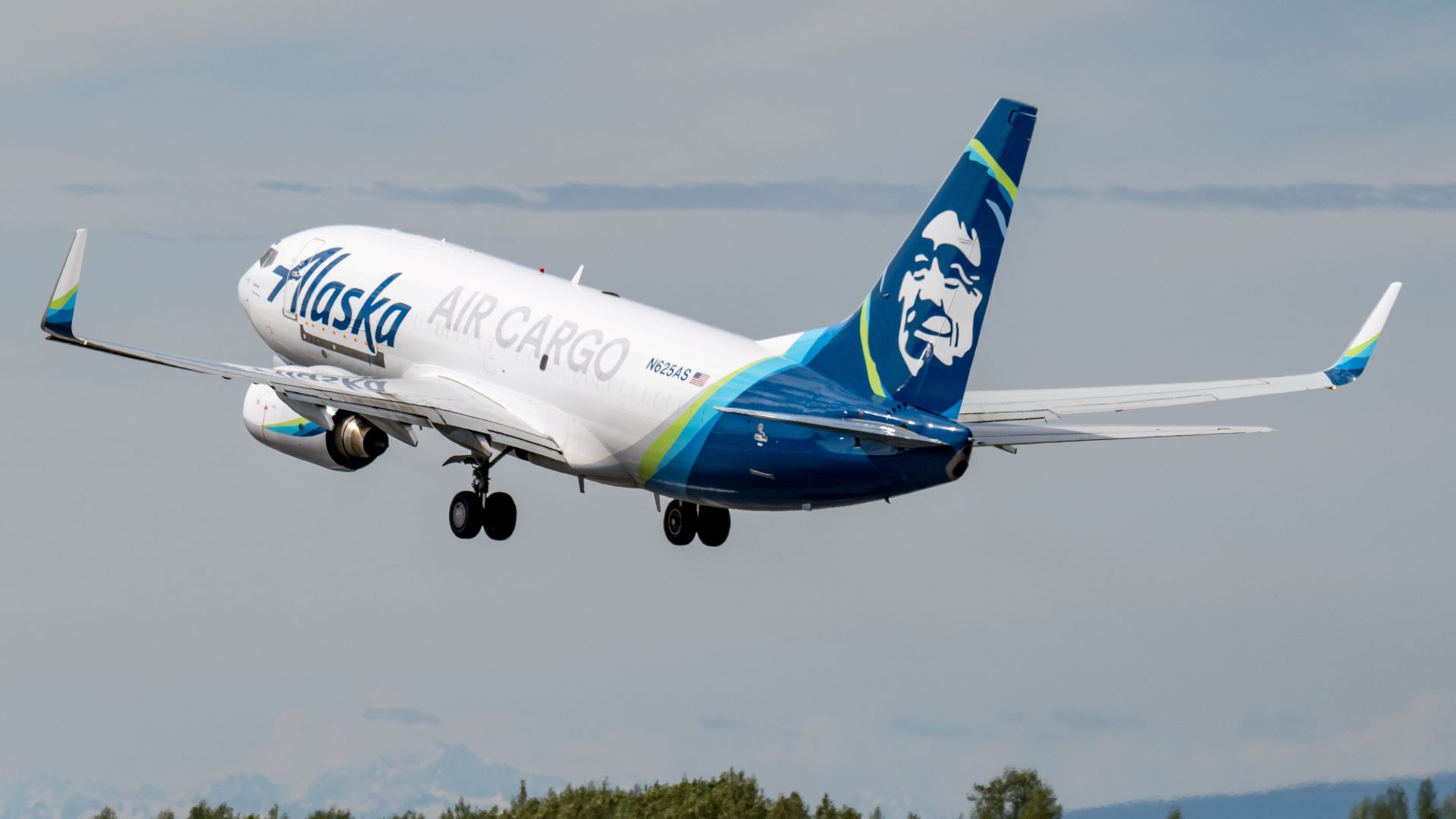 A white Alaska Airlines Cargo jet with blue tail and Eskimo image takes off, rear view.