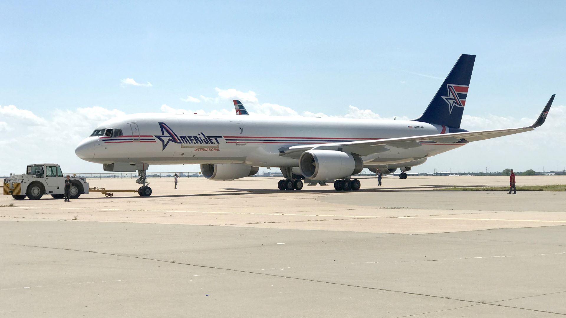 A white Amerijet aircraft with blue tail on the tarmac on a sunny day.