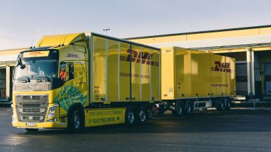 A yellow DHL double-trailer at the warehouse dock.