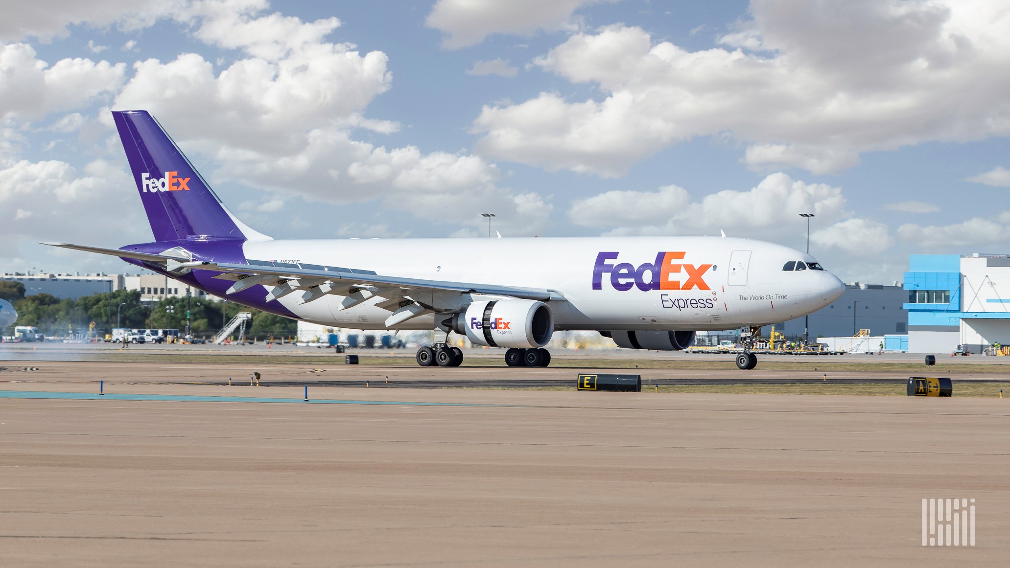 A white and purple FedEx jet on the ground.