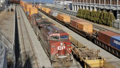 A Canadian Pacific train on train tracks with the port of montreal in the background.