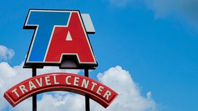 A sign with.the logo of TravelCenters of America with a blue sky in the background