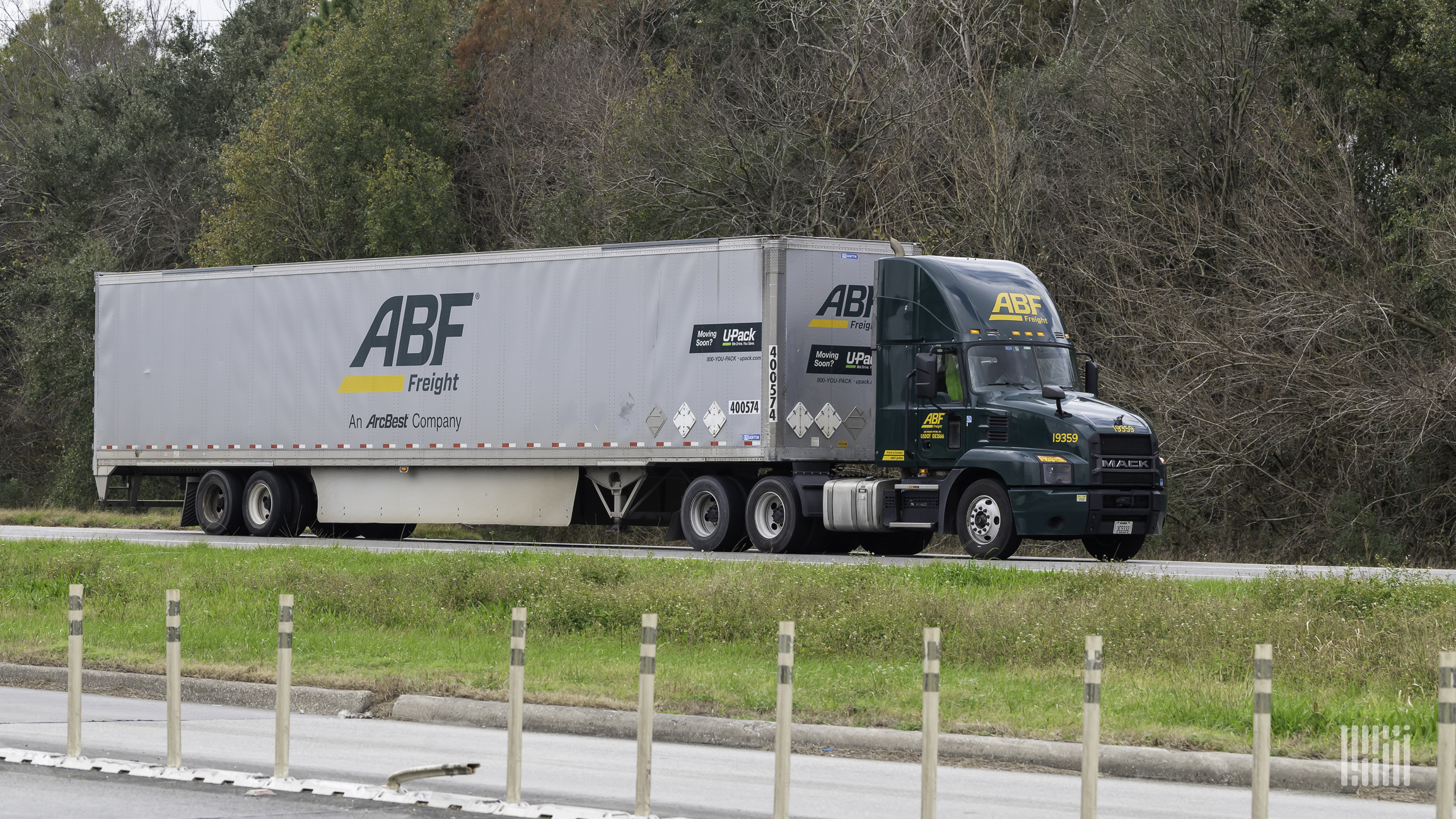 Green ABF truck and gray trailer on highway