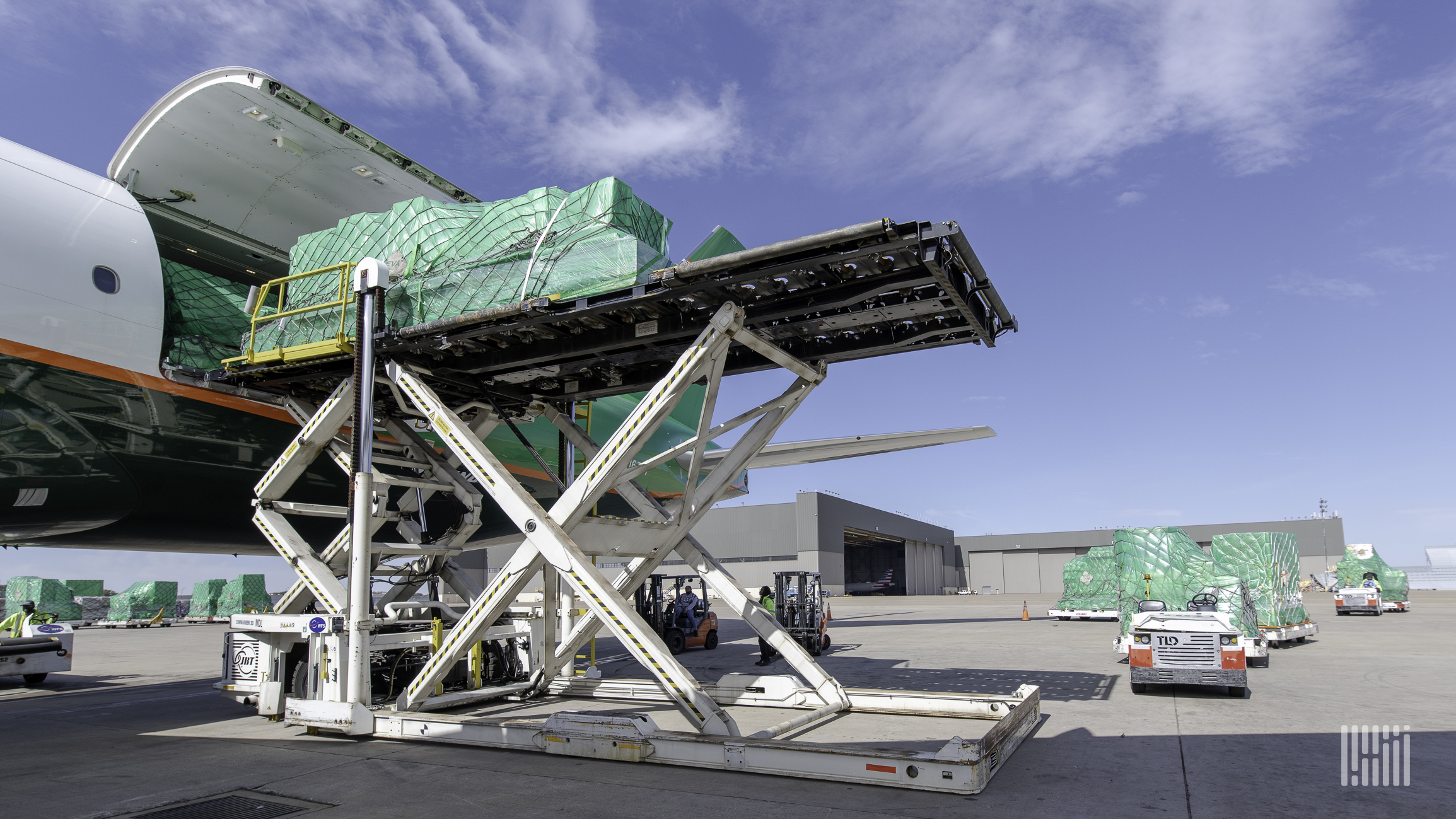 A pallet of cargo on a lift being loaded in the side of a plane.