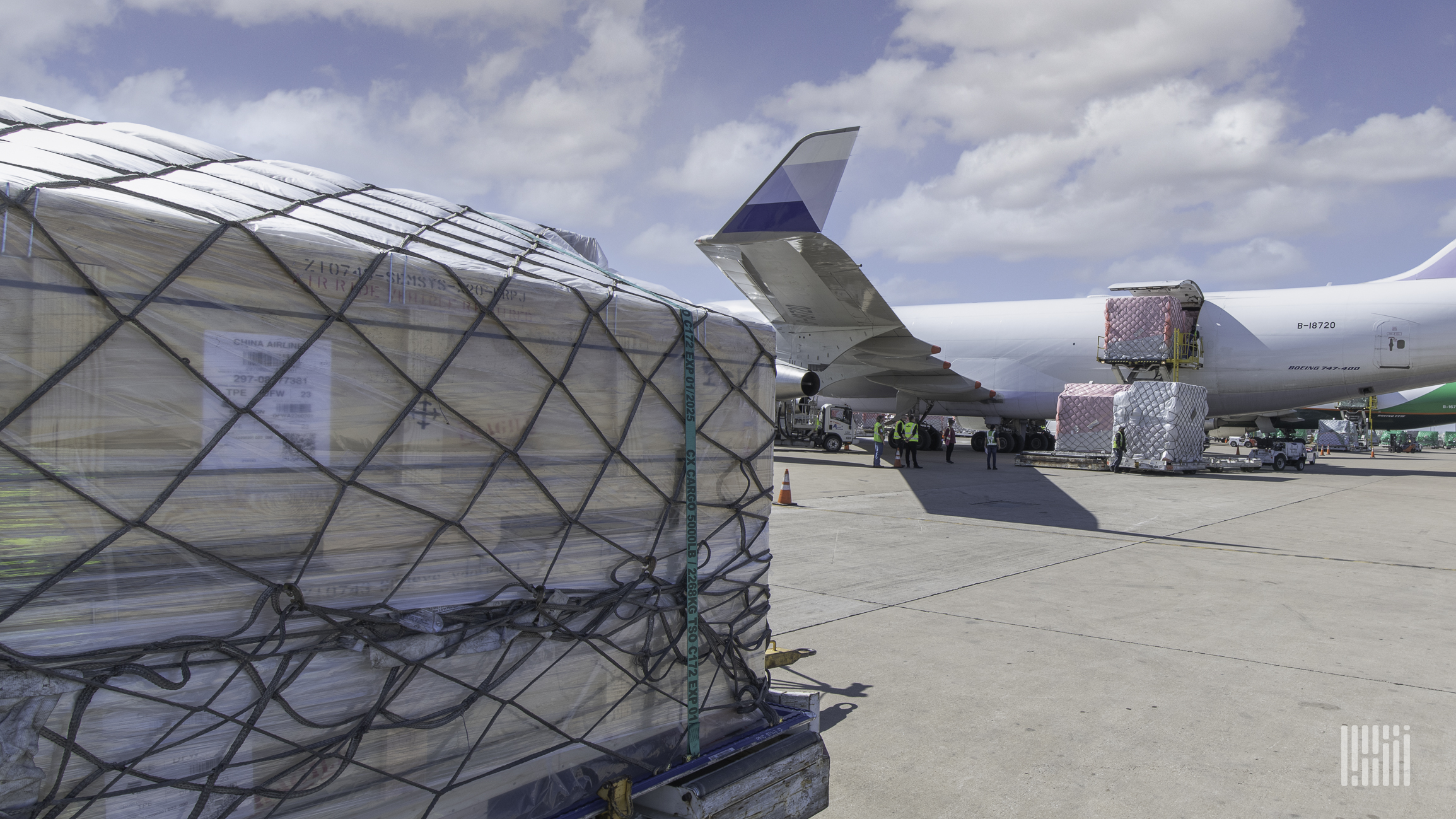 A pallet of cargo with netting sits on tarmac with a large freighter in the background. The air freight recovery stumbled in March because of the Ukraine war and other factors.