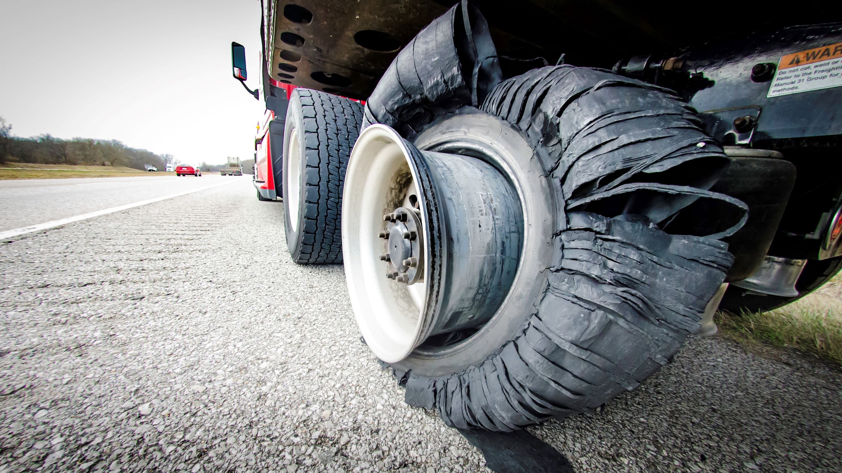 A mangled tire on the rim of a semi