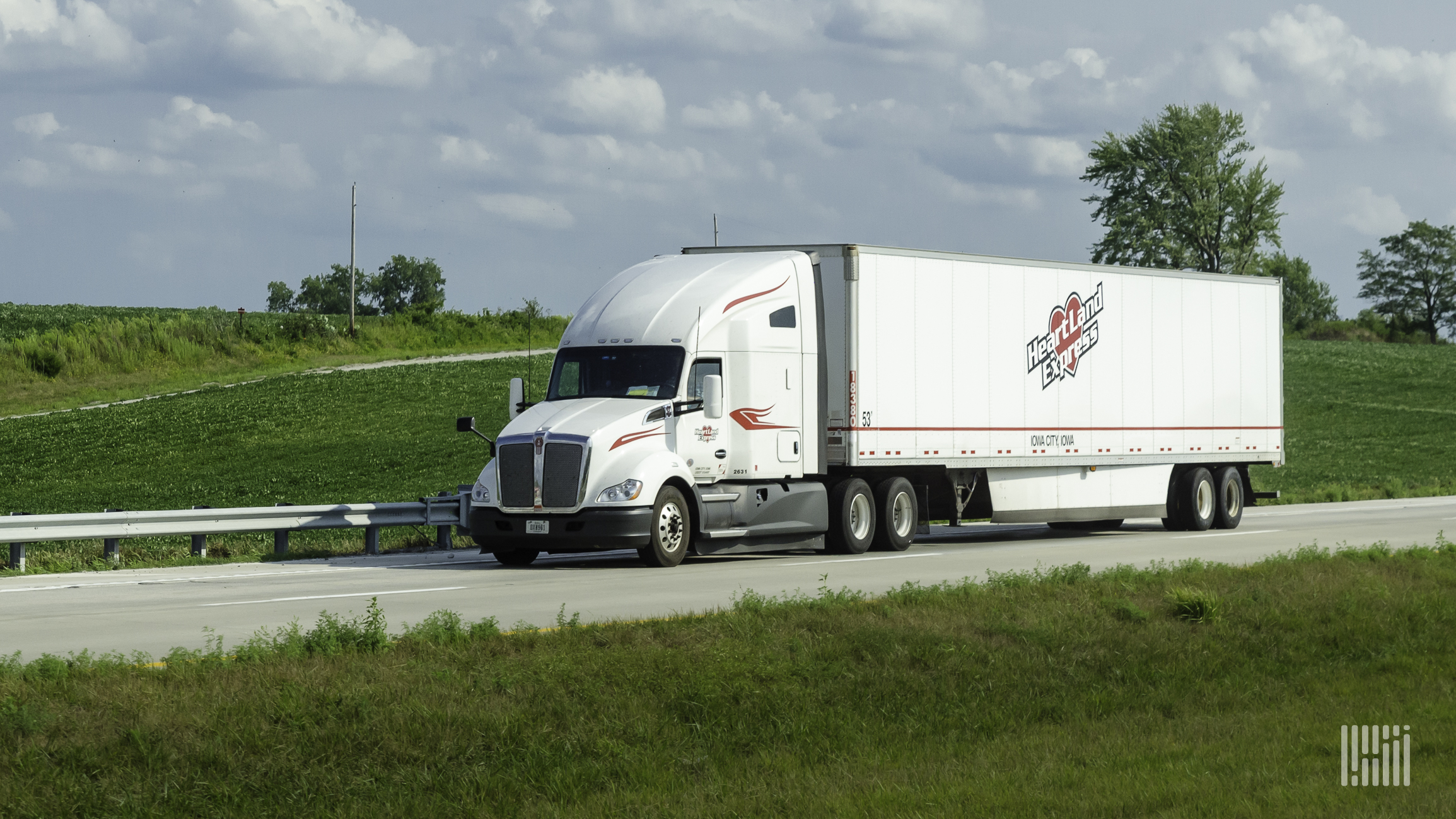 A white Heartland Express tractor and trailer on the highway