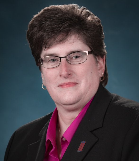 A portrait of Beth Rooney, who is wearing glasses and a blazer,