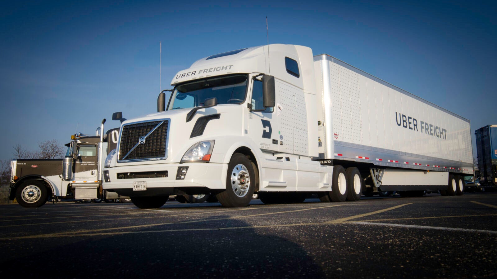 A white tractor-trailer with the black logo of Uber Freight written on the trailer