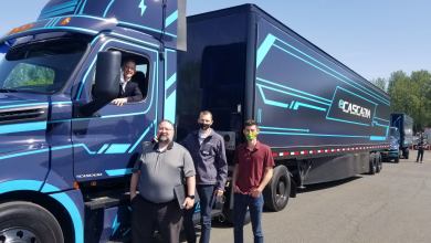 Titan Freight CEO sits at the wheel of a navy Freightliner eCascadia electric truck.