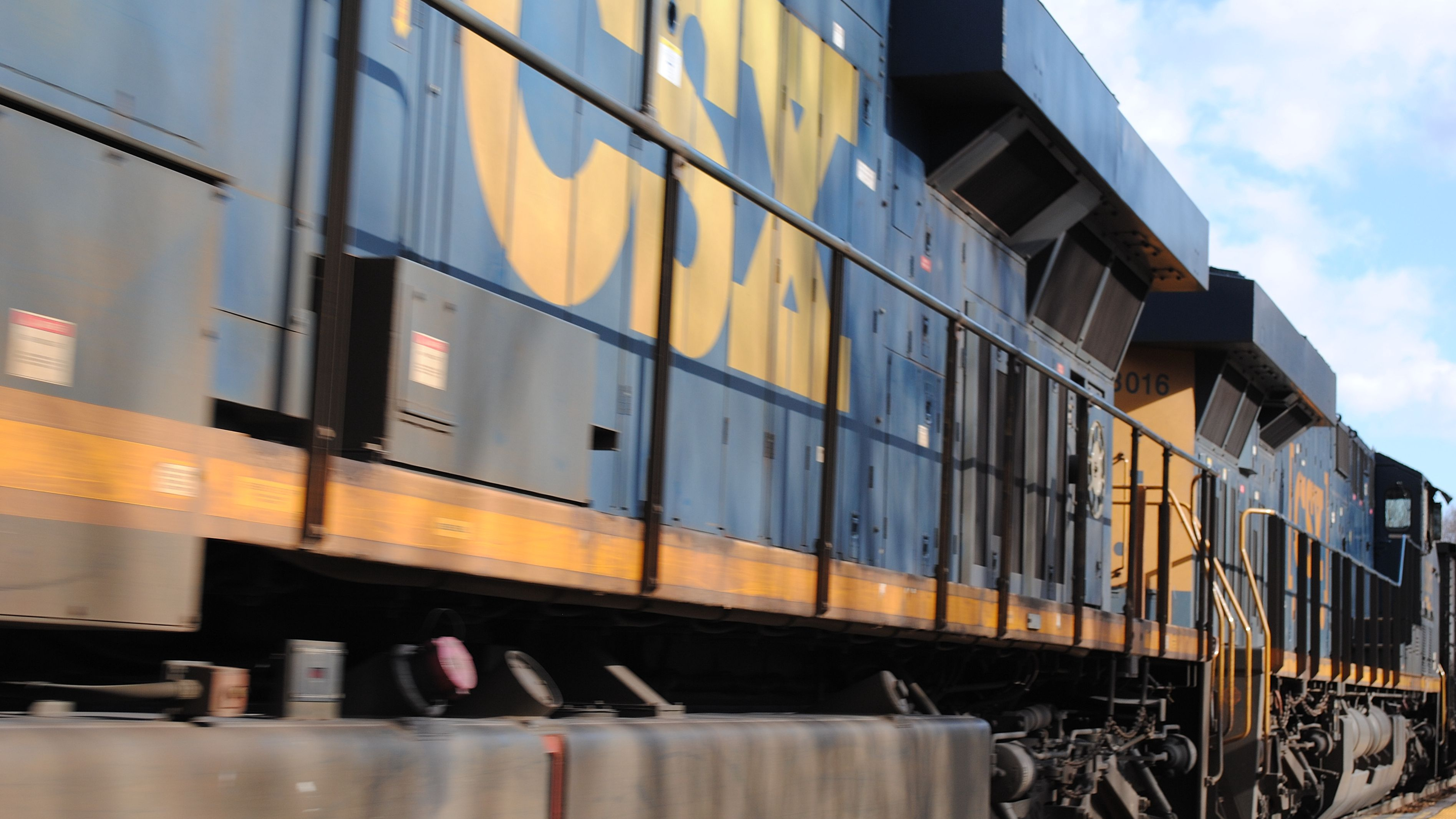 A blue freight train with a yellow logo of the rail operator CSX