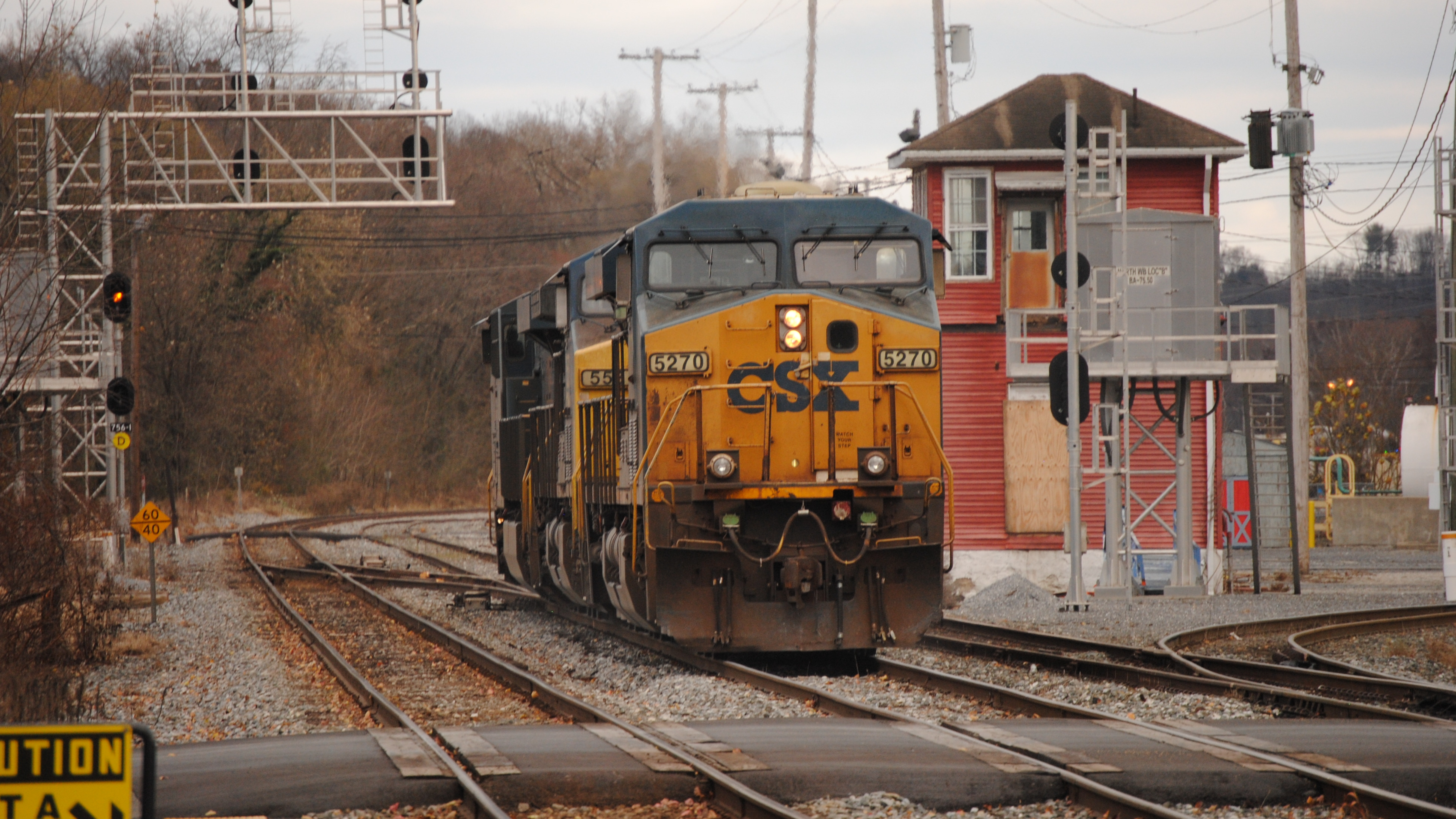 A photograph of a CSX train on a track nearby a rail yard.