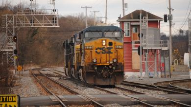 A photograph of a CSX train on a track nearby a rail yard.
