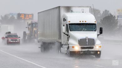 A White tractor, silver trailer on highway in rain storm