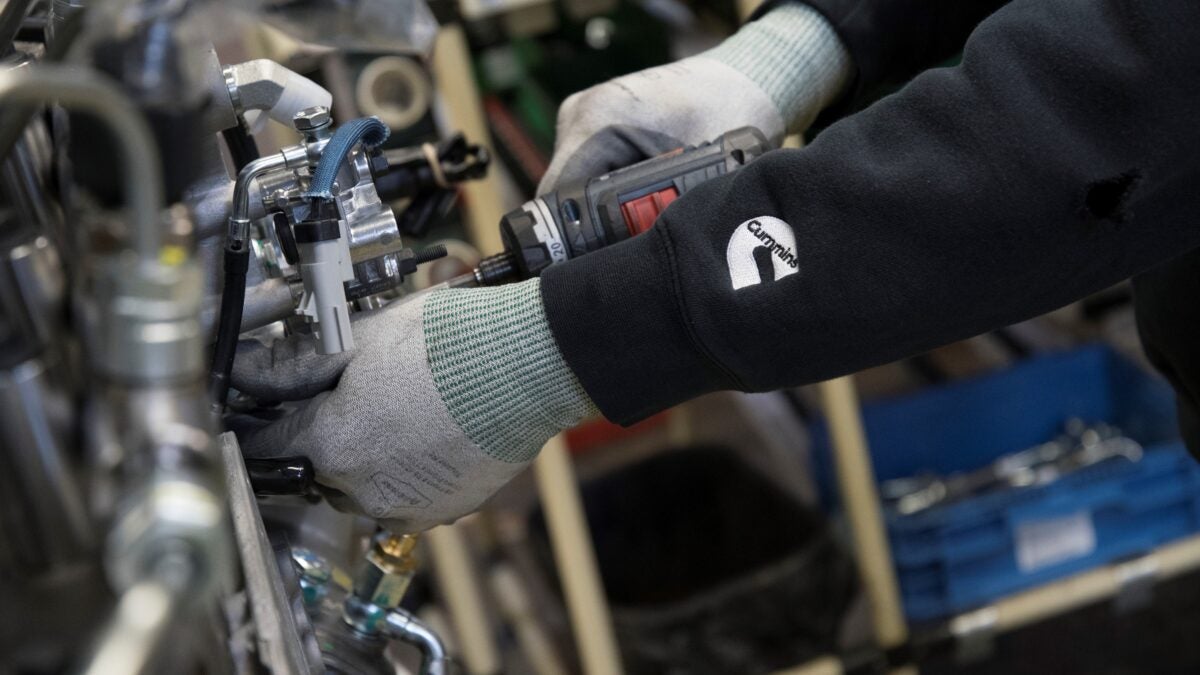 A Cummins worker adjusting an engine on a production line.