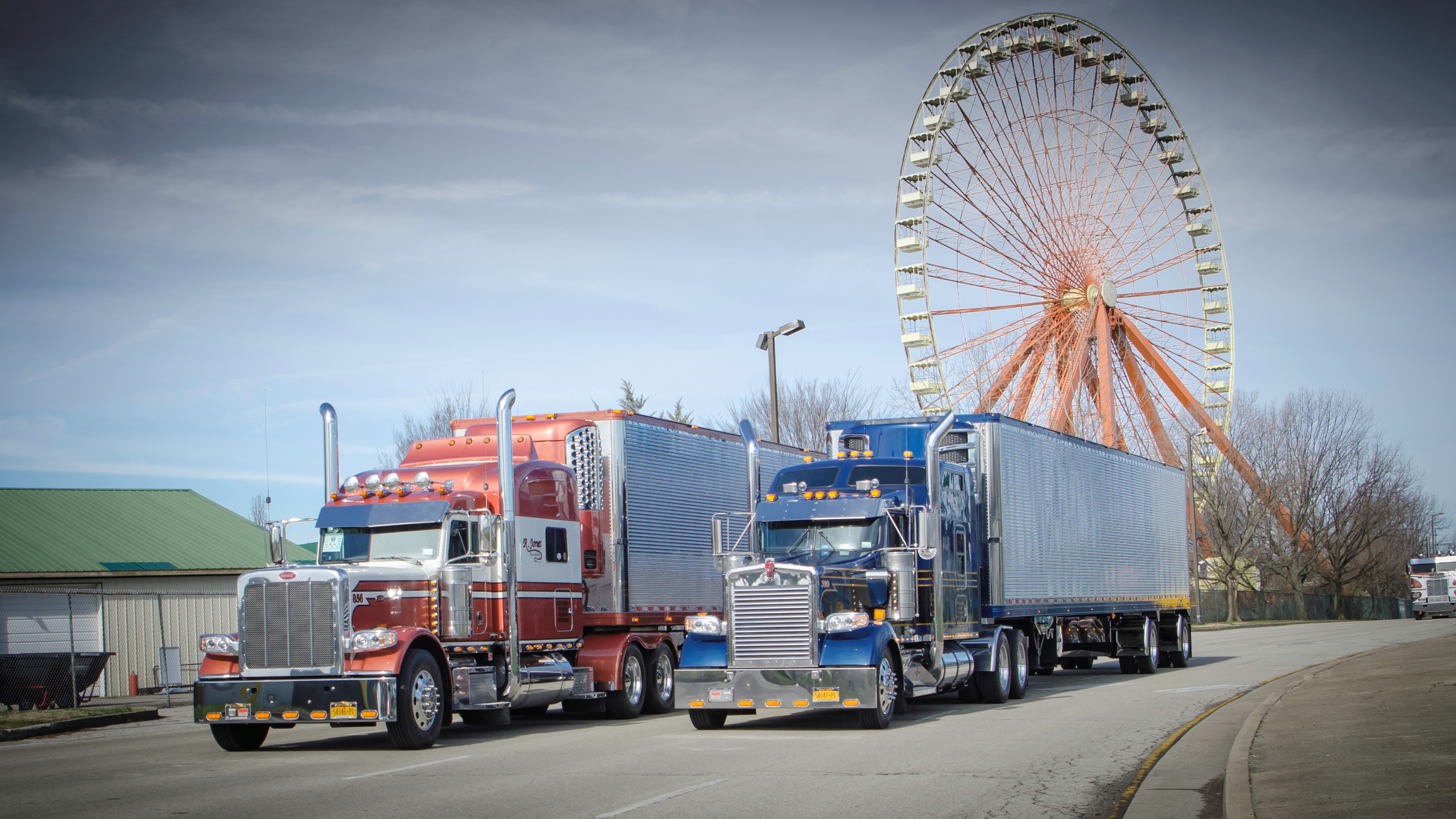 Two Peterbilt trucks with ferris wheel in background