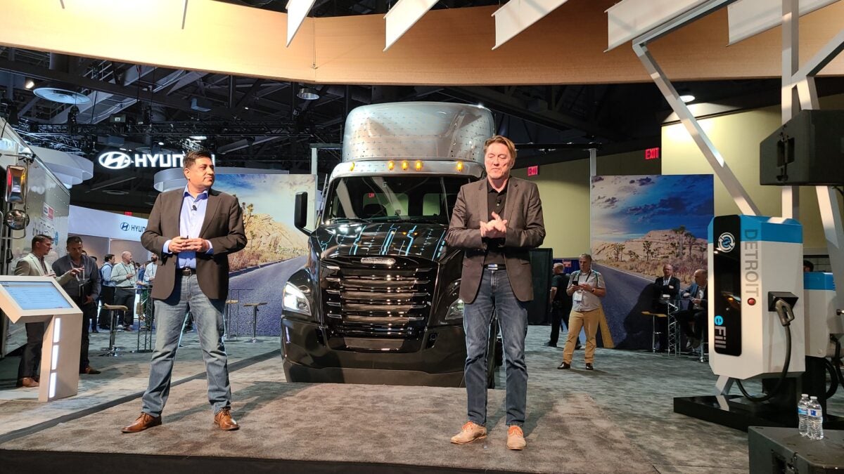 DaimlerTruck executives in front of black Freightliner eCascadia electric truck.