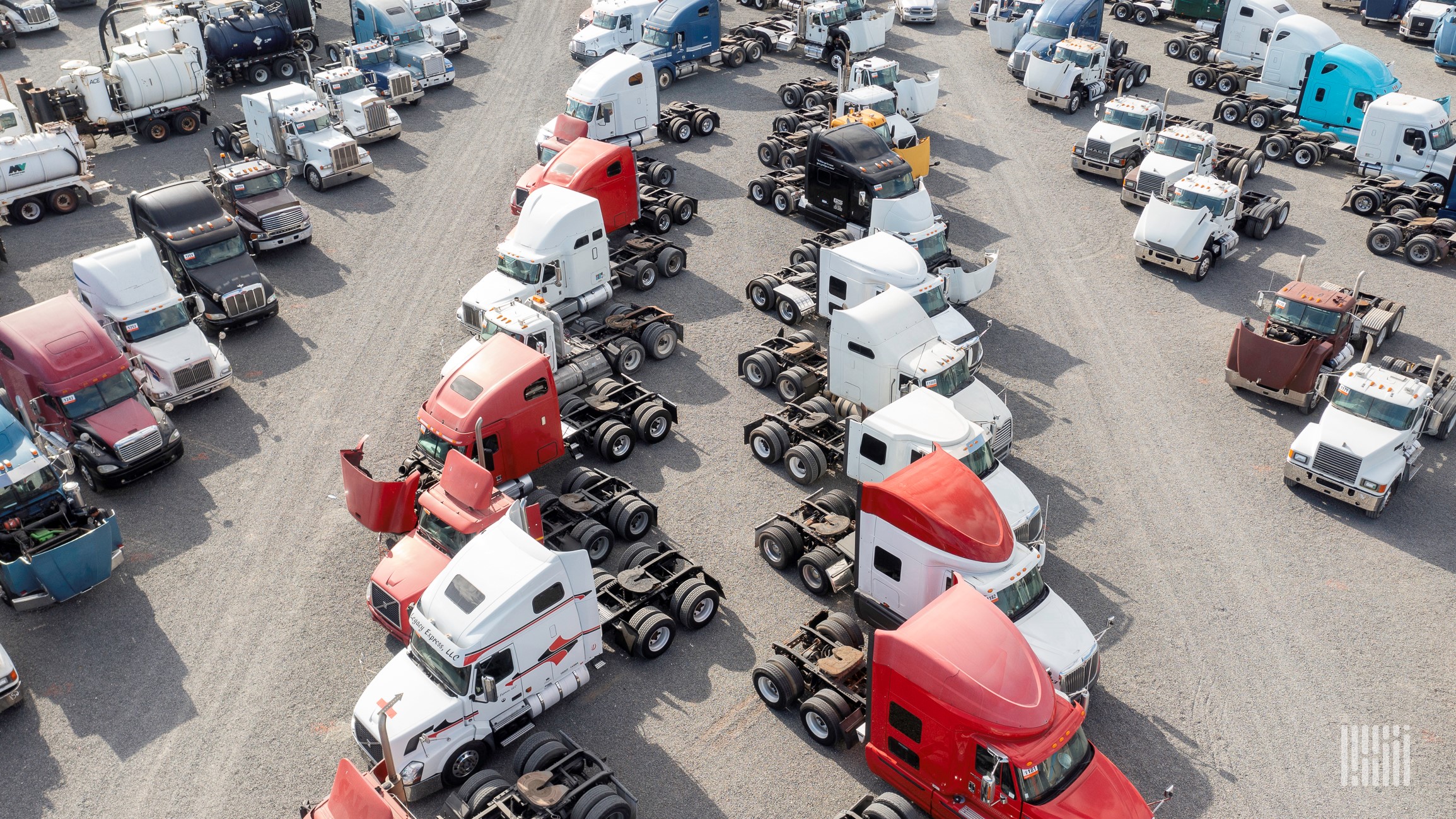 Aerial view of multi-colored used trucks in an auction parking lot.