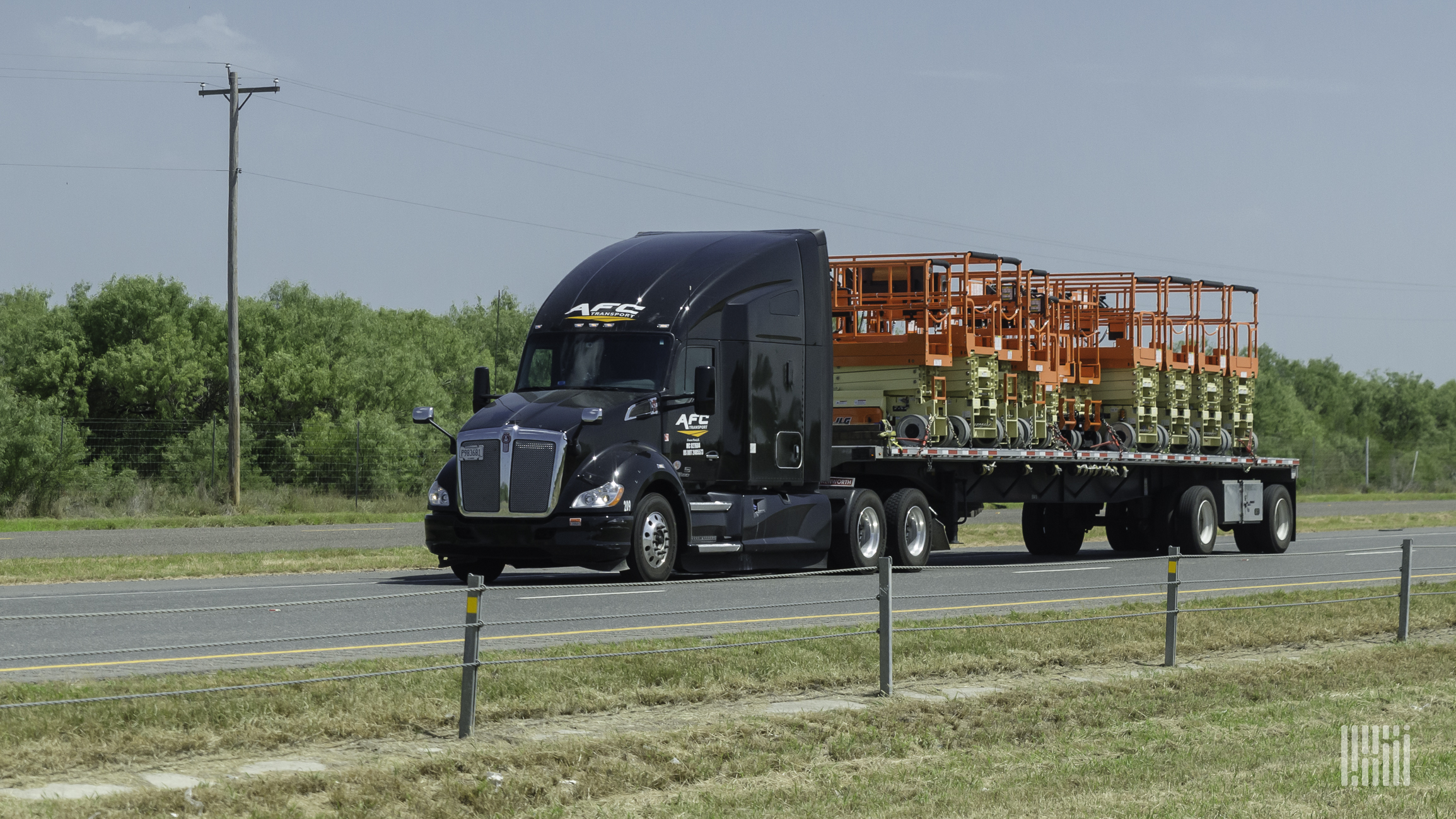 A black AFC Transport tractor trailer is traveling down a major road.