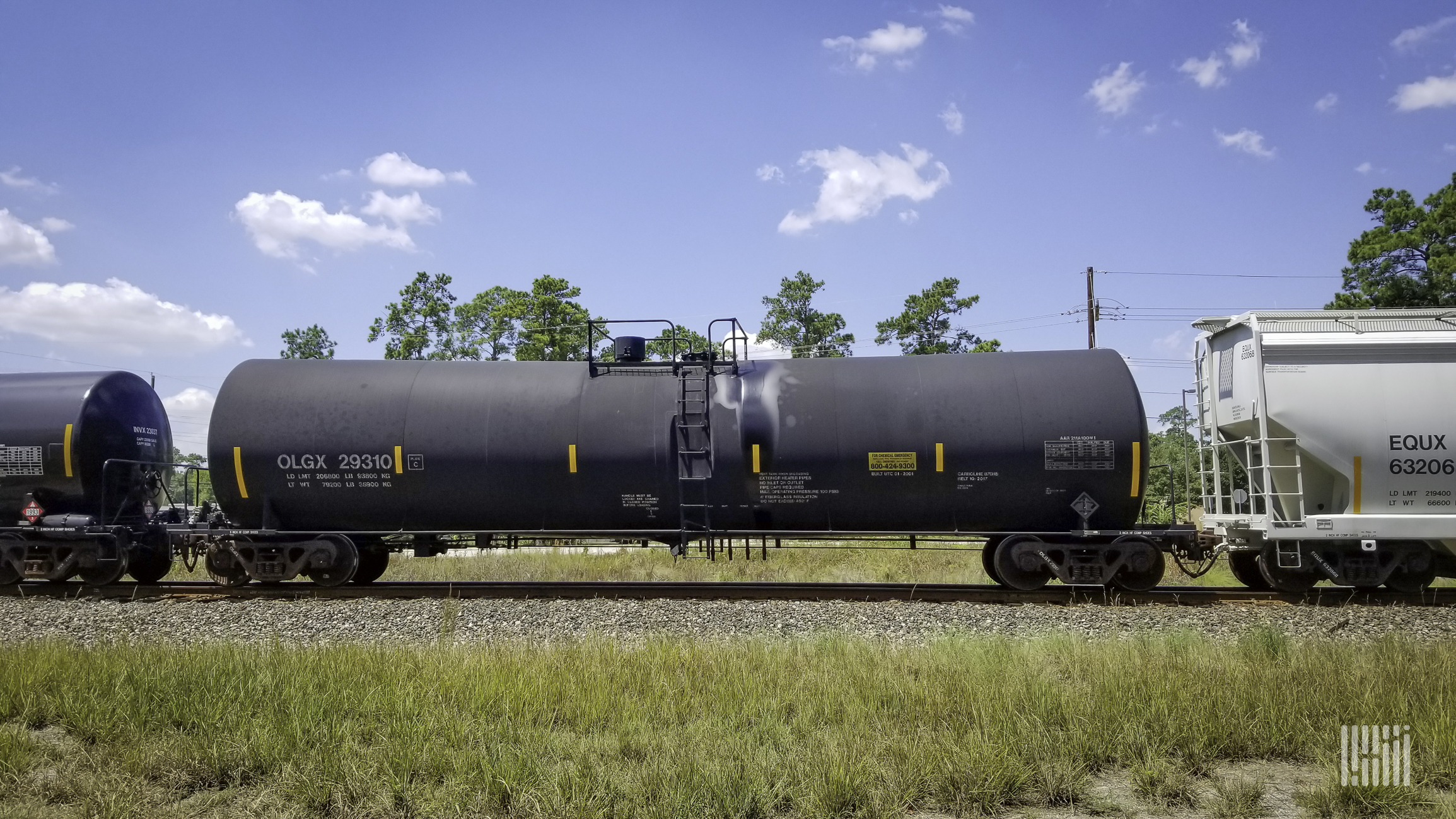 Two tank cars and a hopper car travel on the railroad.