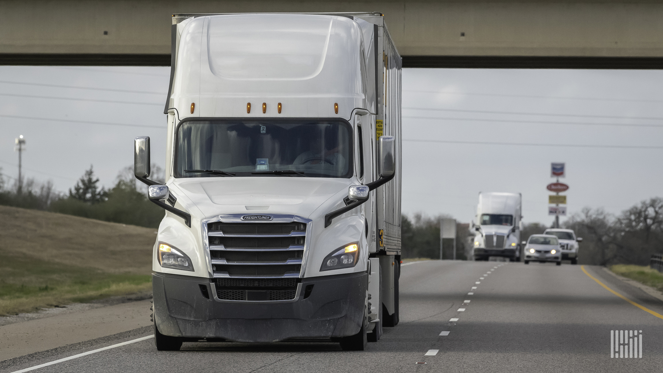 A white tractor hauling a white trailer on the highway