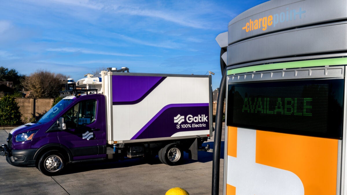 Electric box truck parked next to a charging station.